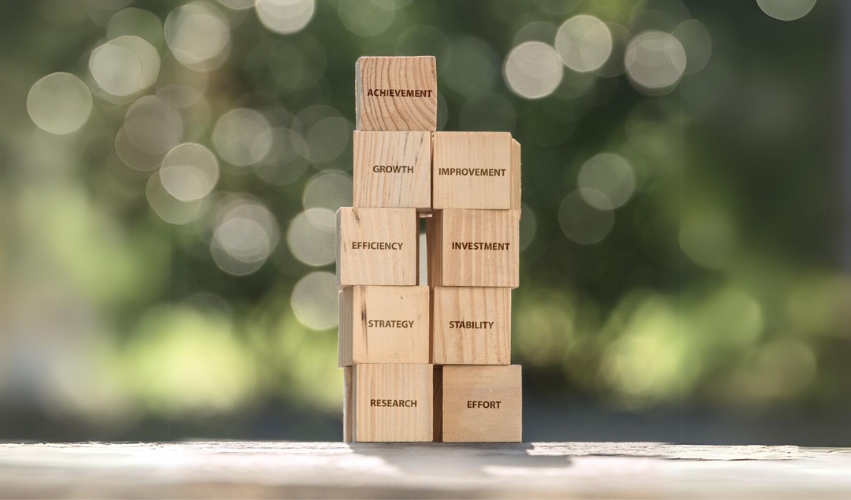 Building blocks with motivational and business words describing business confidence index, on bokeh green background
